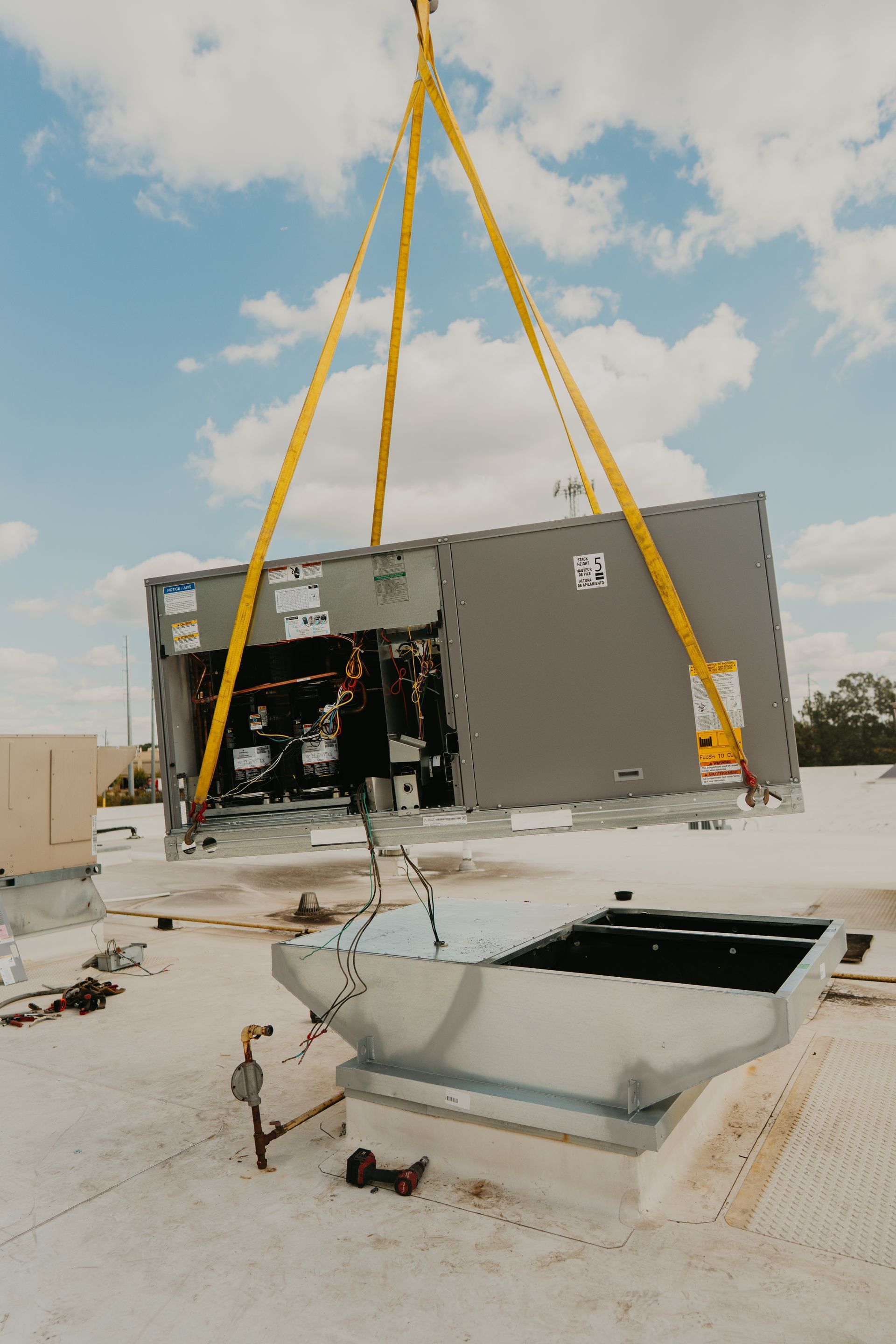 A crane is lifting a large piece of equipment on top of a building.