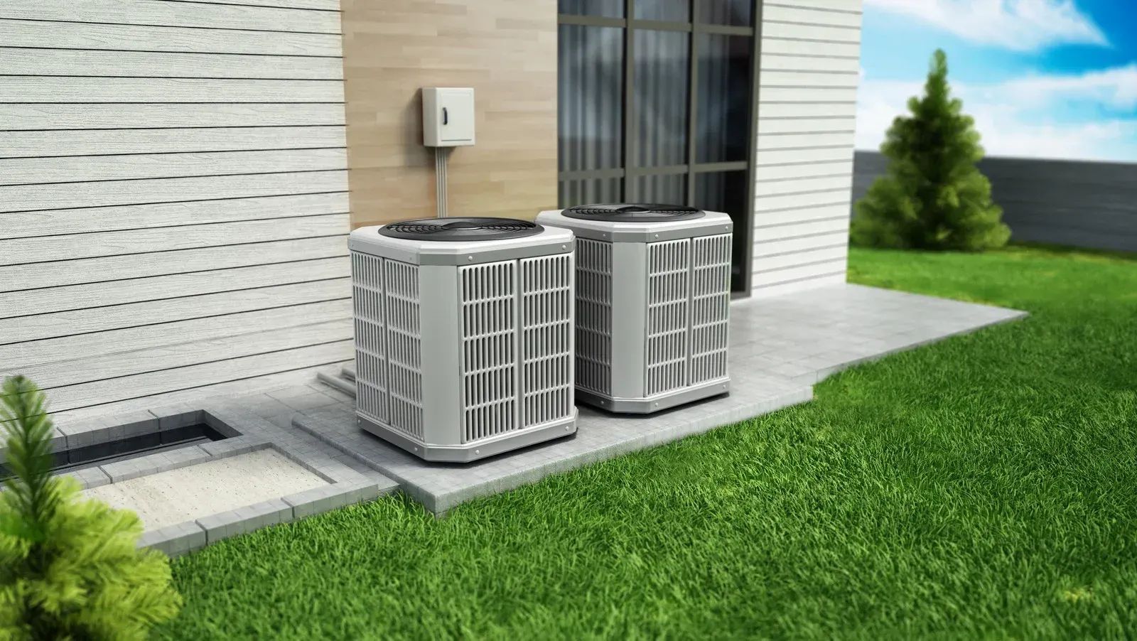 Two gray outdoor HVAC condenser units sit on a concrete pad next to a light-colored house with a grassy lawn.