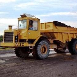 Un camión volquete amarillo está estacionado al costado de la carretera.