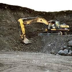 Una excavadora amarilla está cavando en un montón de tierra.