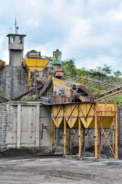 Una gran máquina amarilla está sentada frente a un muro de piedra.