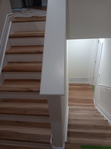 Indoor staircase with wooden steps and white walls, split view showing a hallway and stair landing