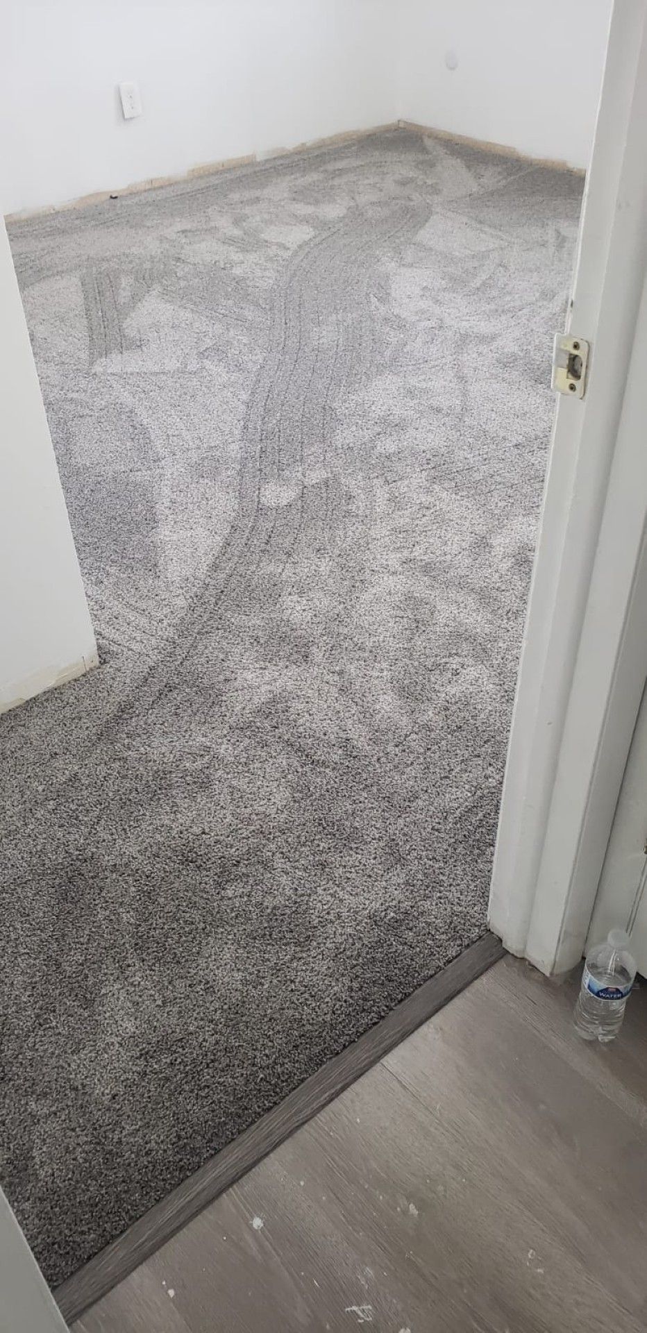 Empty room with gray carpet and white walls, viewed through a doorway