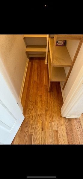 Narrow wooden closet or pantry with open shelving and drawers, viewed from the doorway.