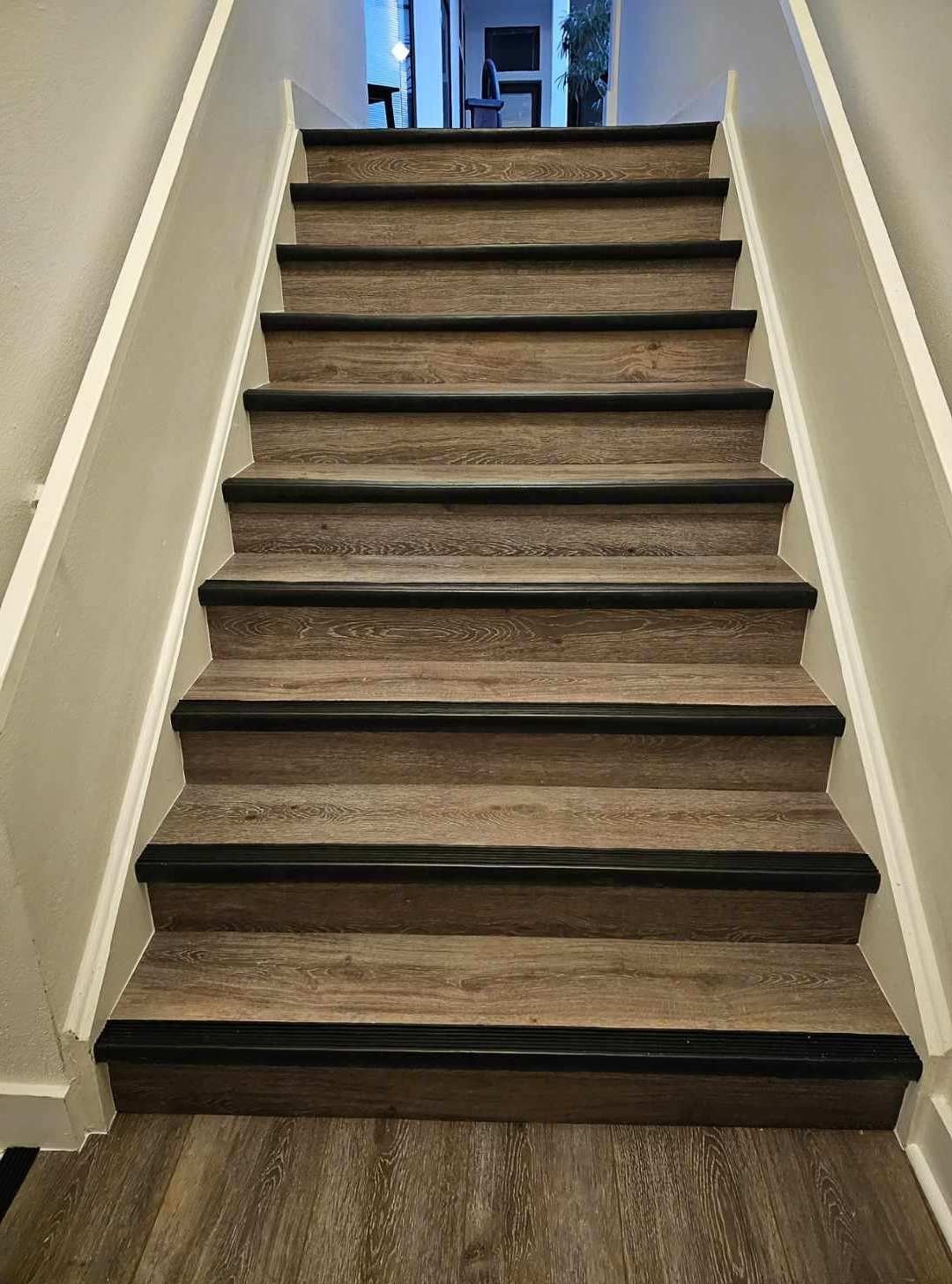 Carpeted indoor staircase with beige walls and white handrails leading upward