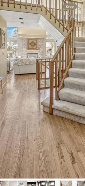 Bright entry hall with carpeted staircase, wood railing, and hardwood floor leading to a living room.