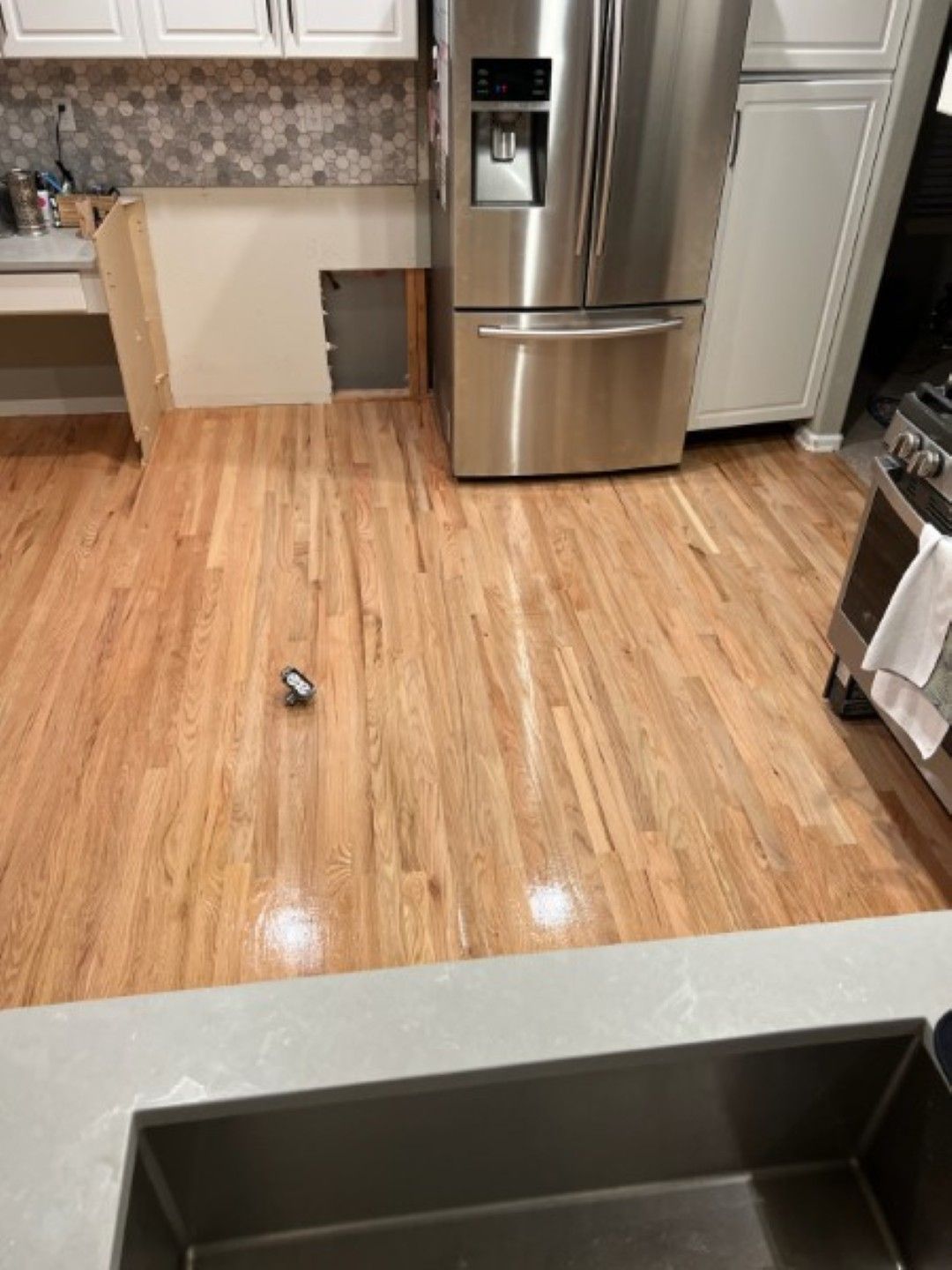 Kitchen with stainless steel fridge, hardwood floor, and a sink in the foreground