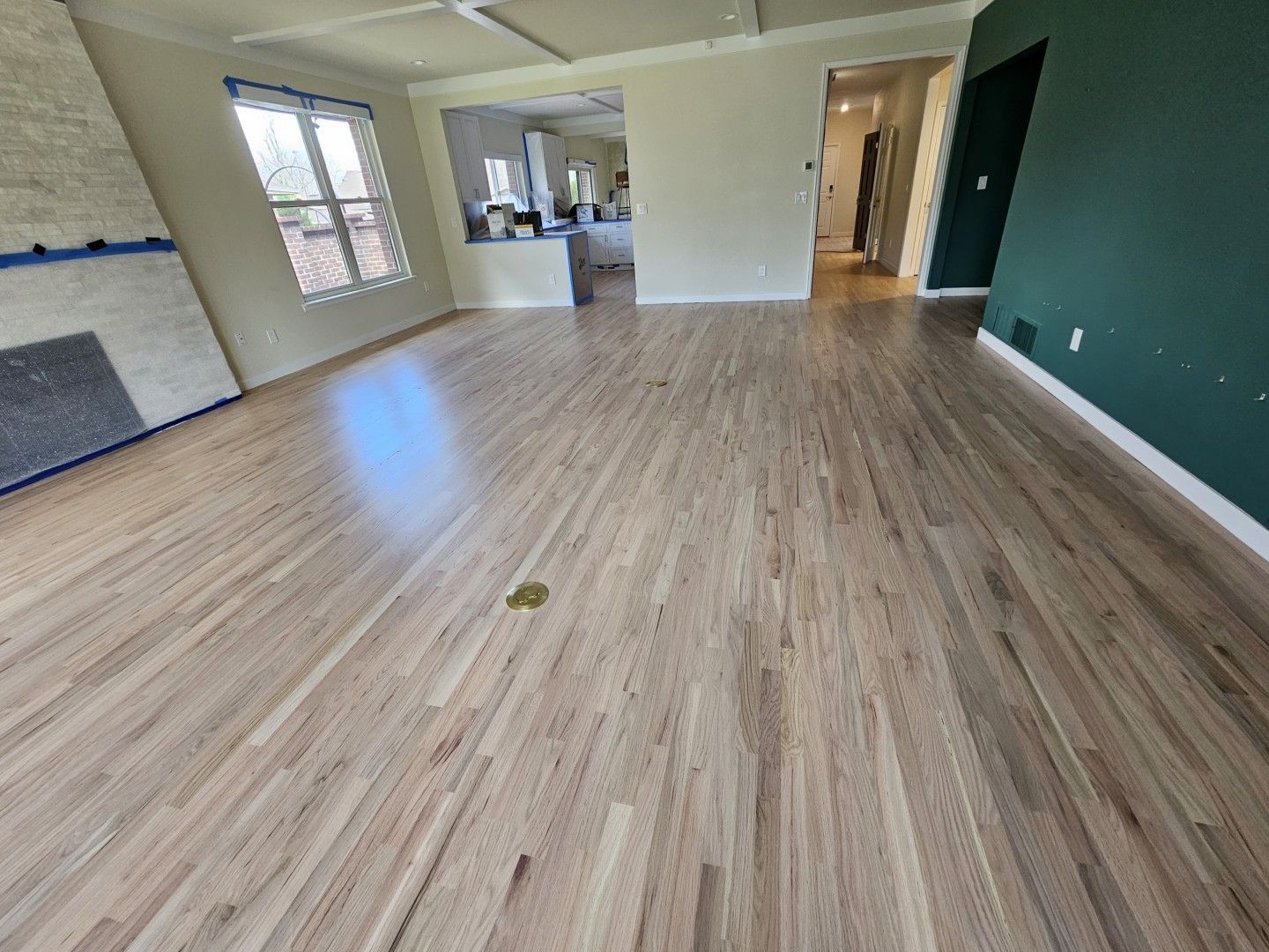 Empty living room with light wood floors, white walls, and a green accent wall.