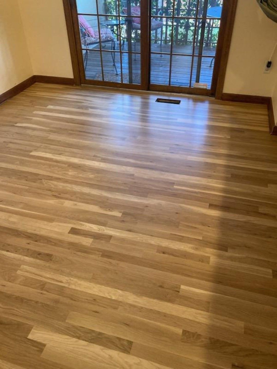 Empty wood-floored room with sliding glass doors and a balcony view