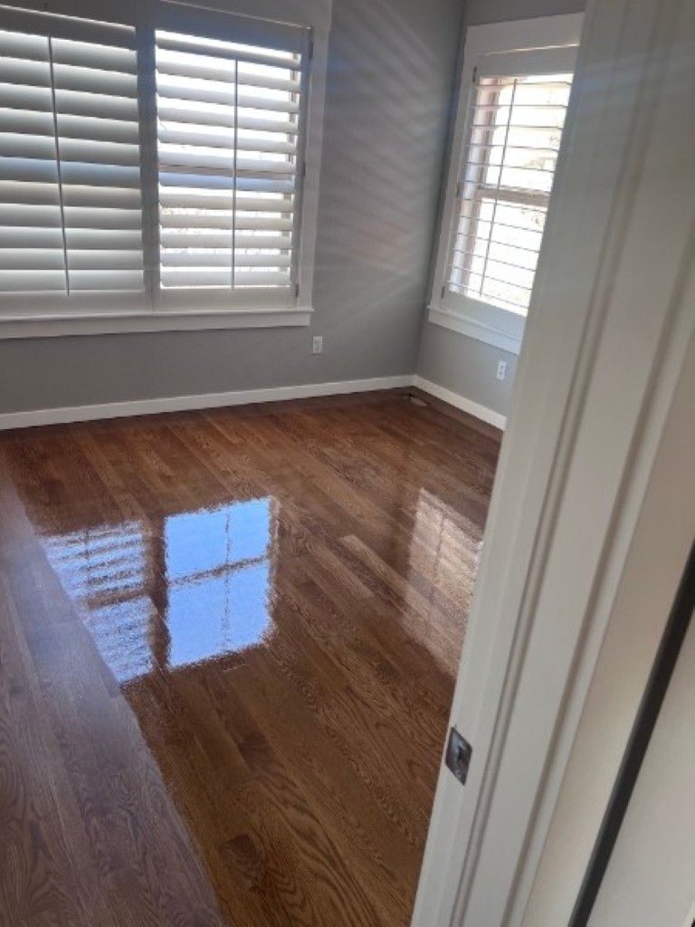 Empty bedroom with glossy hardwood floor and white shutters letting in daylight