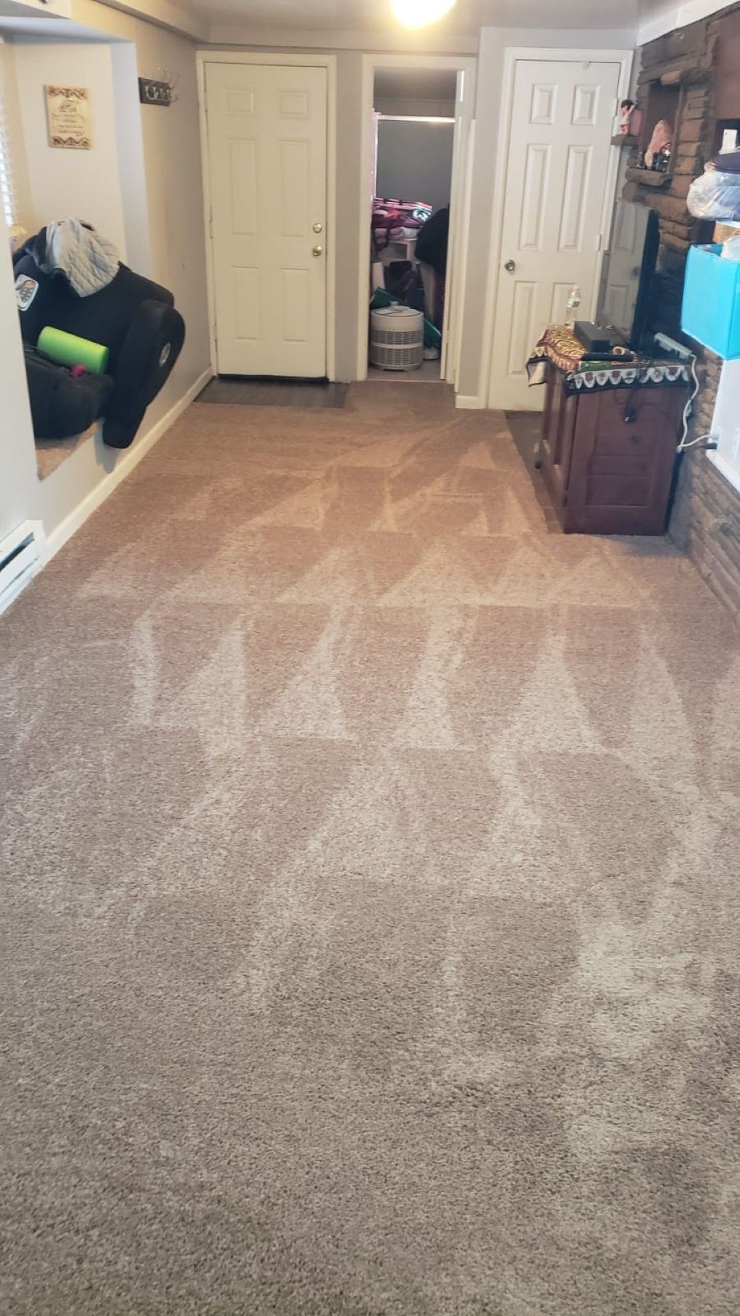 Carpeted hallway with white doors, shelving on the right, and a chair on the left.