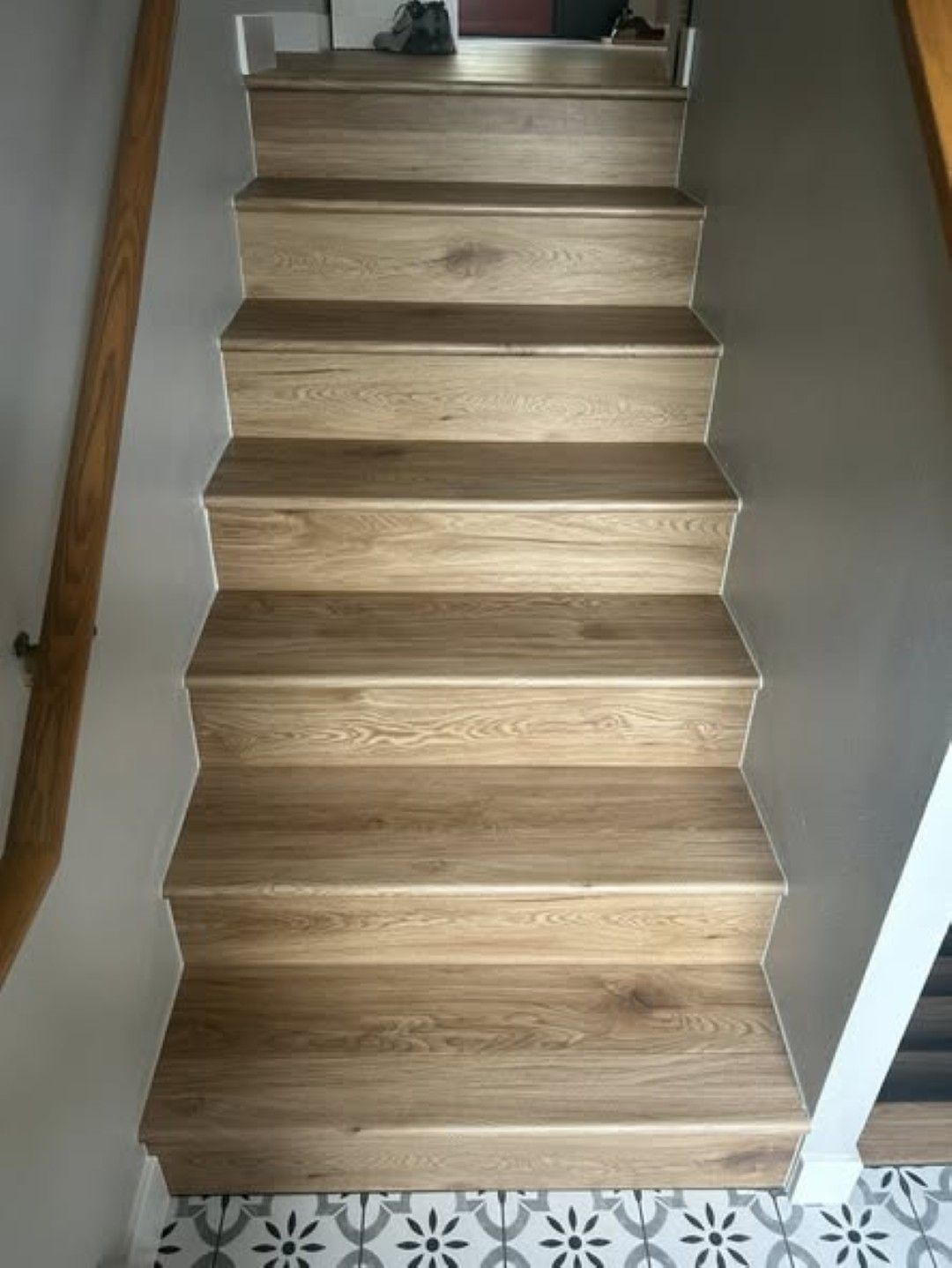 Wooden staircase with light oak treads and white trim, viewed from the bottom hallway.