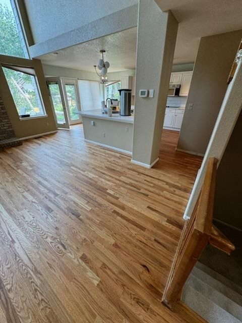 Bright open-plan kitchen and living room with hardwood floors, large windows, and a central island.