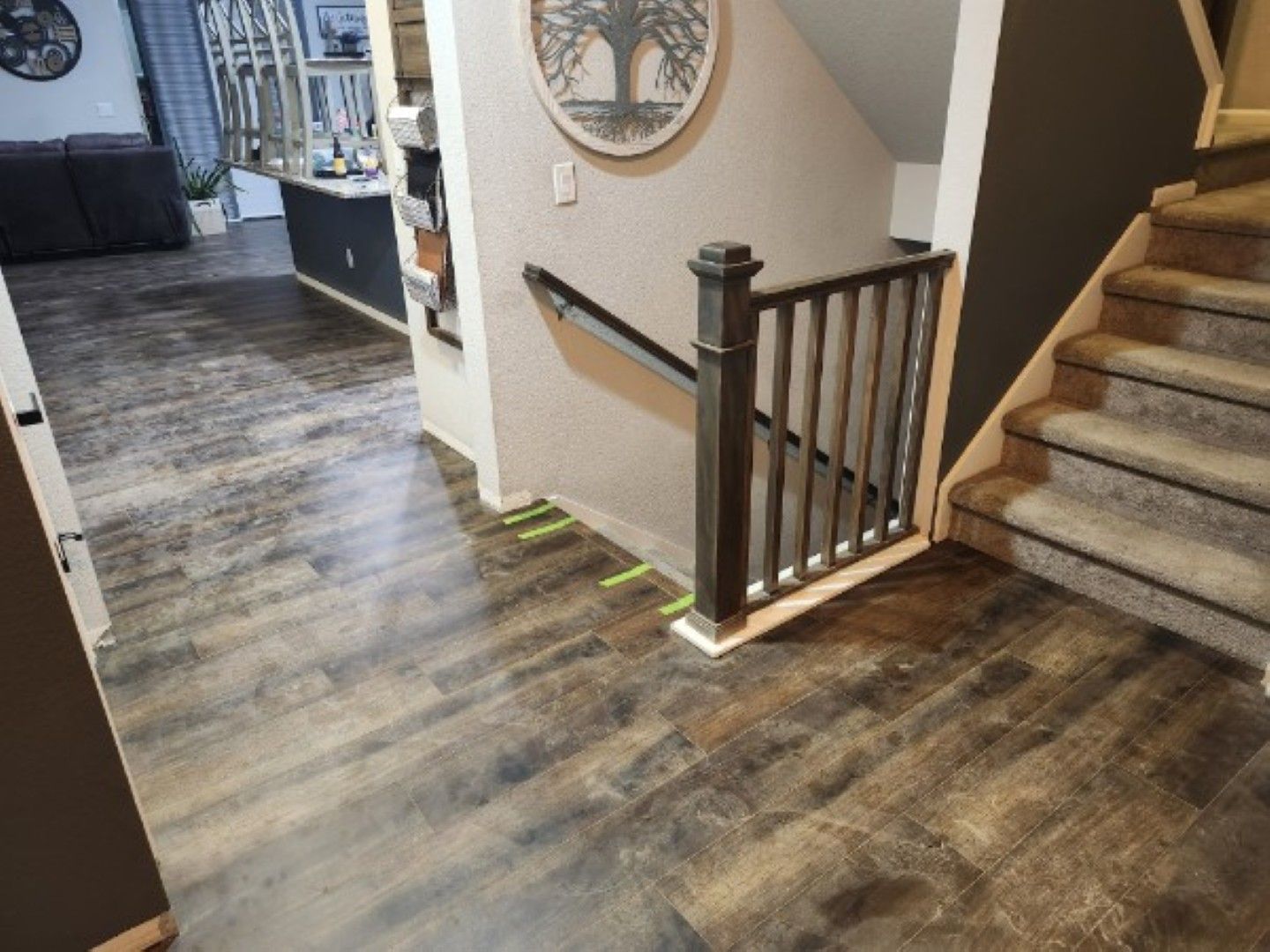 Hallway with dark wood floors, staircase, and a small landing railing beside a wall mirror