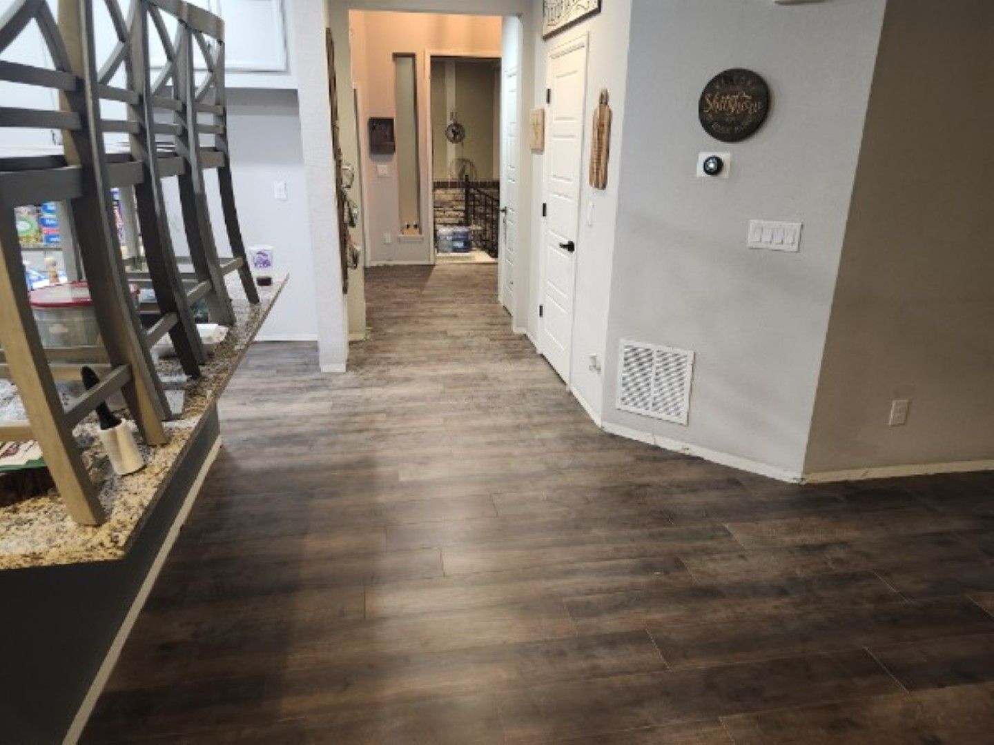 Modern hallway with wood-look flooring, white walls, and a staircase on the left.