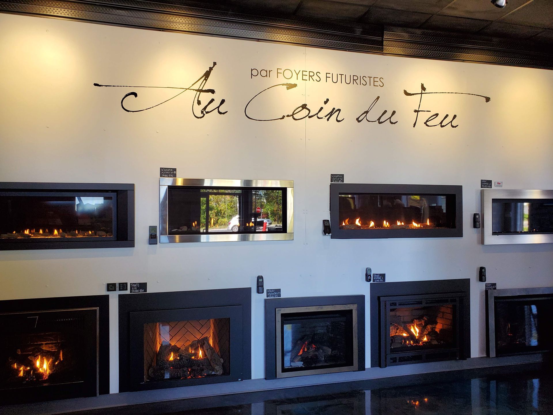 Fireplace showroom with various gas fireplaces on display, illuminated with warm light.