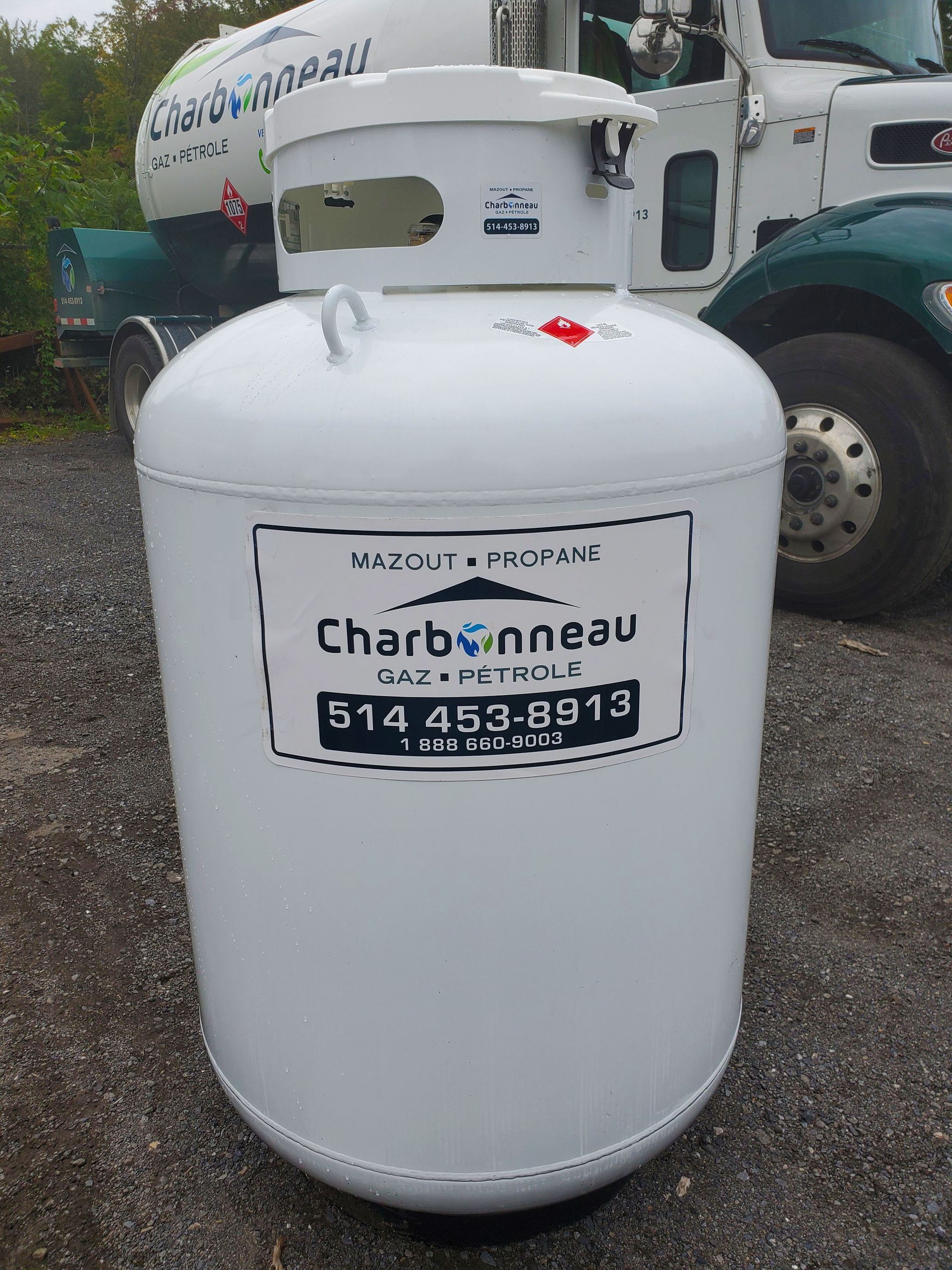 Réservoir de propane blanc portant le nom de la compagnie « Charbonneau » imprimé dessus.