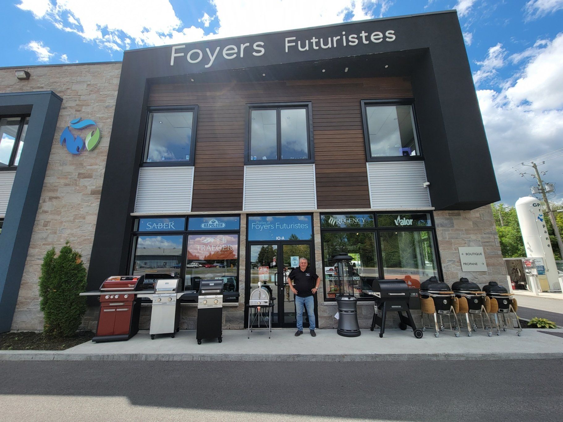 Façade du magasin Foyers Futuristes avec des barbecues exposés, une personne debout à l'extérieur.