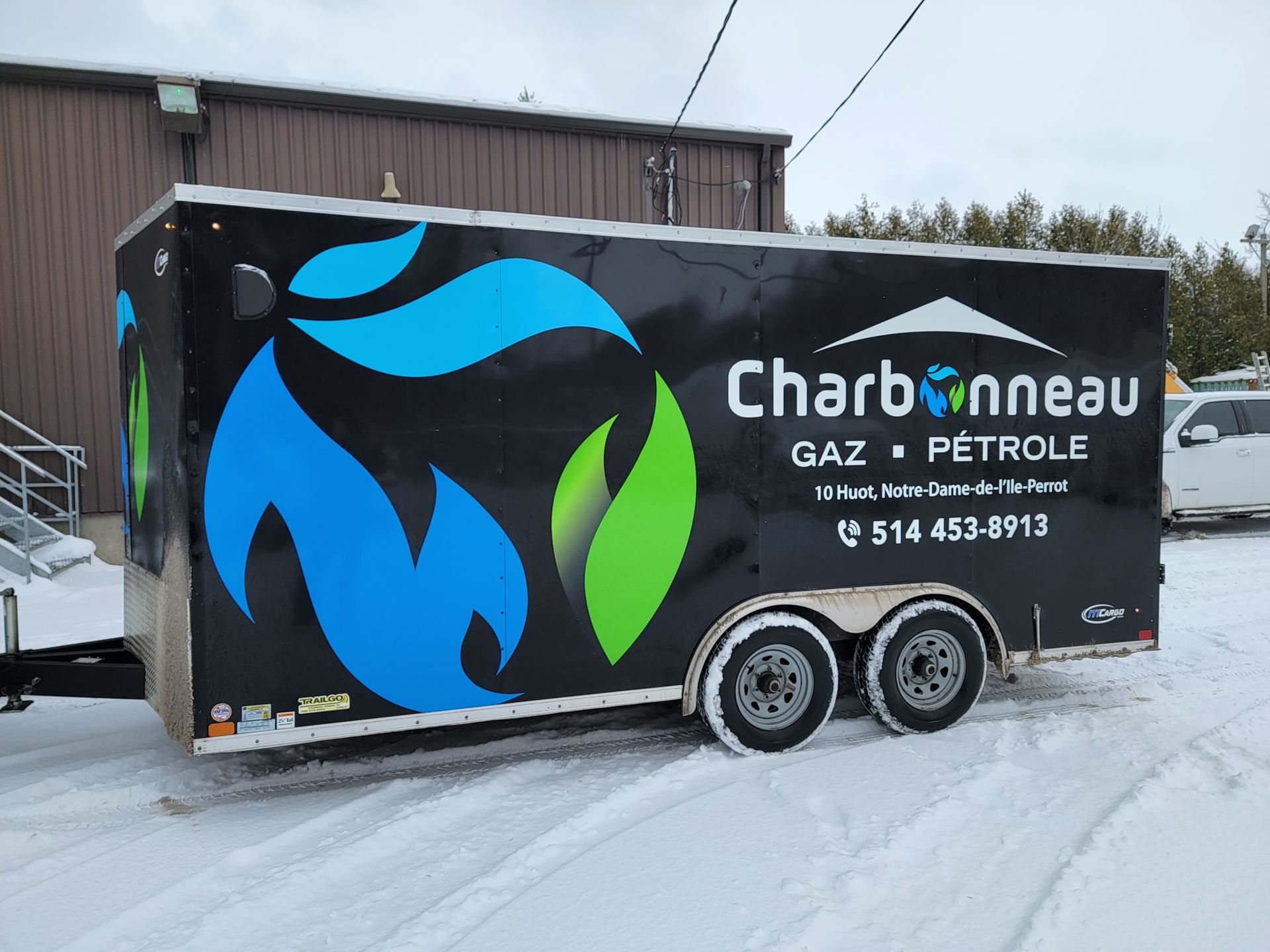 Remorque noire avec logo Charbonneau Gaz Petrole par une journée enneigée.