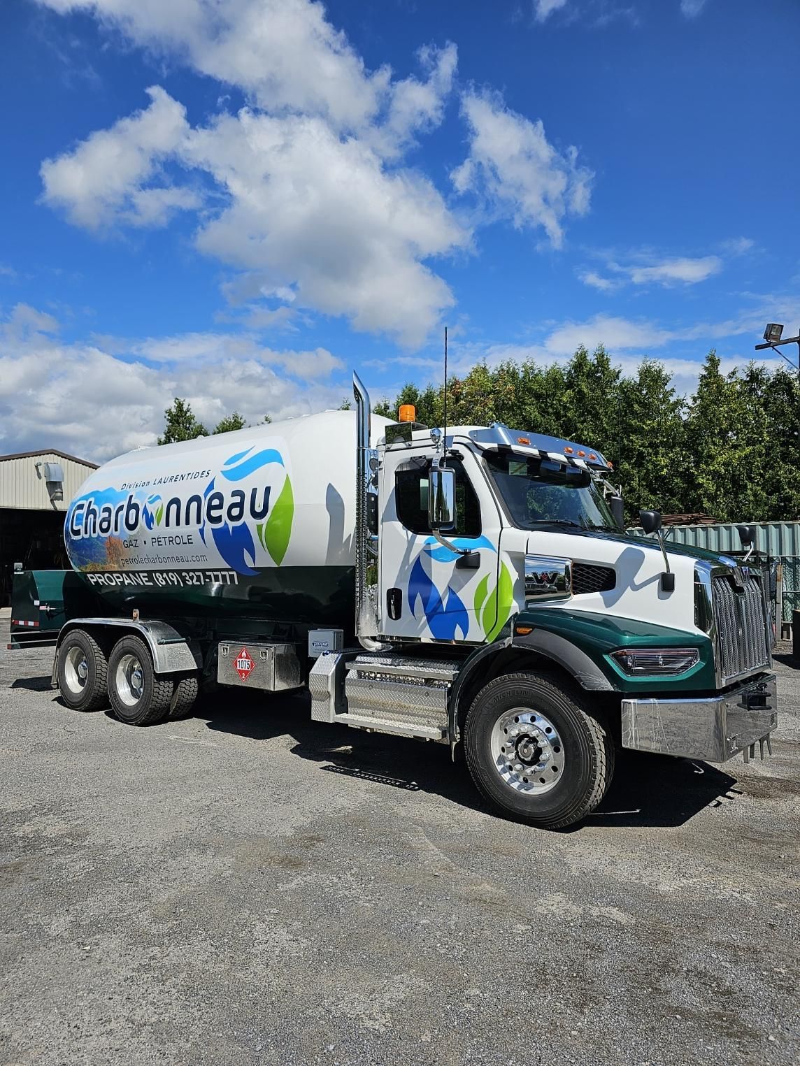 Un gros camion-citerne blanc avec des touches de vert et de bleu est garé dehors par temps nuageux.