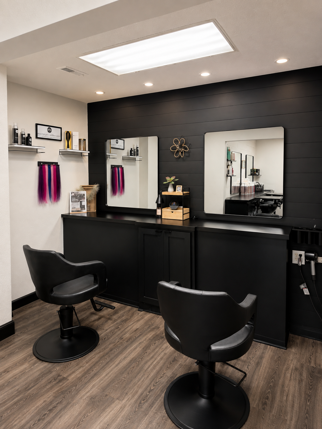 Modern salon interior with two styling chairs, mirrors, and black counters under bright ceiling lights