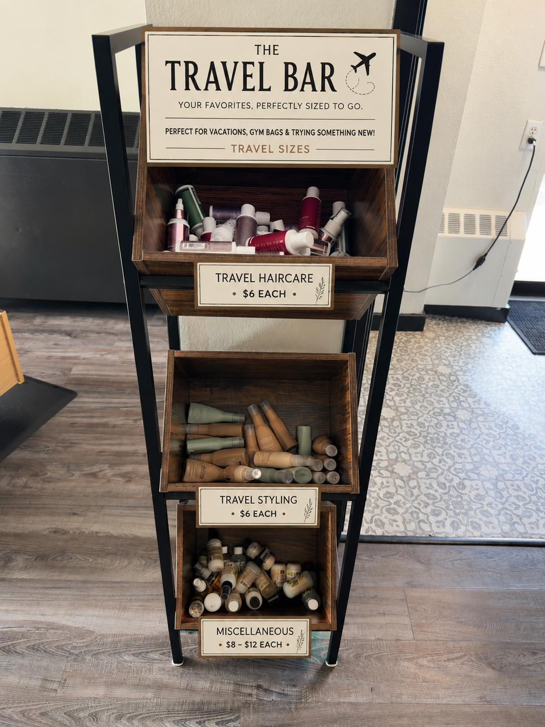 Wooden travel bar shelf with labeled bottles and bar tools in an indoor setting