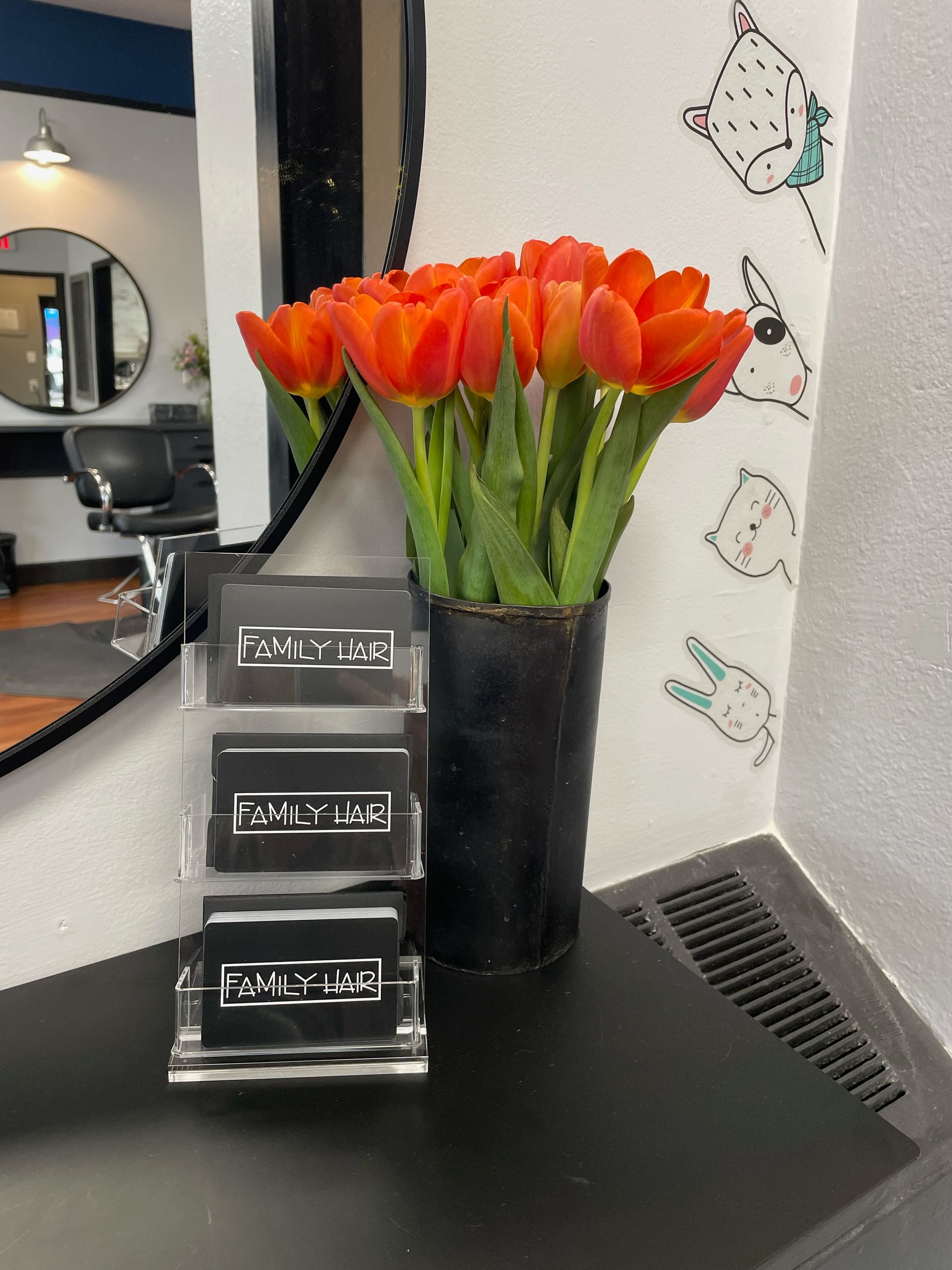 A vase of orange tulips sits on a table in front of a mirror
