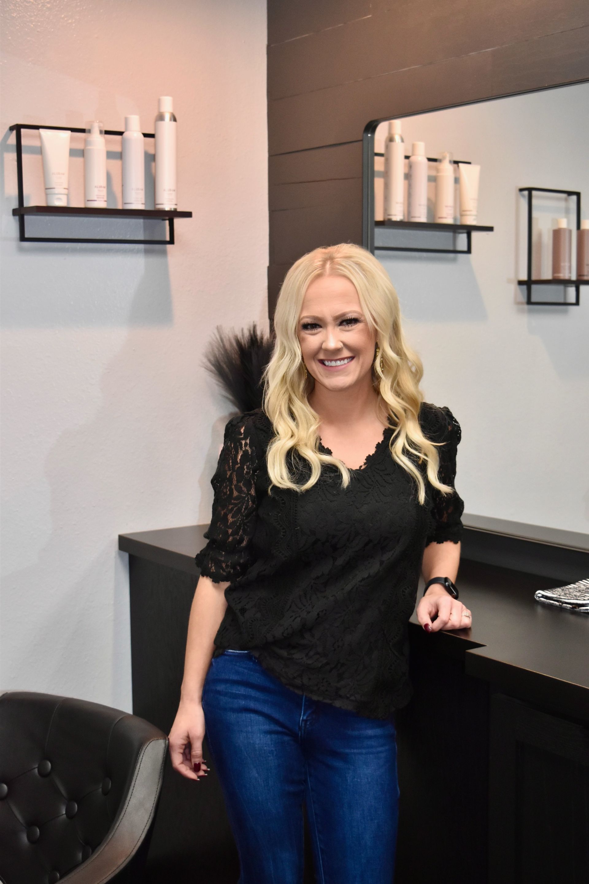 A woman in a black top and blue jeans is standing in a room.