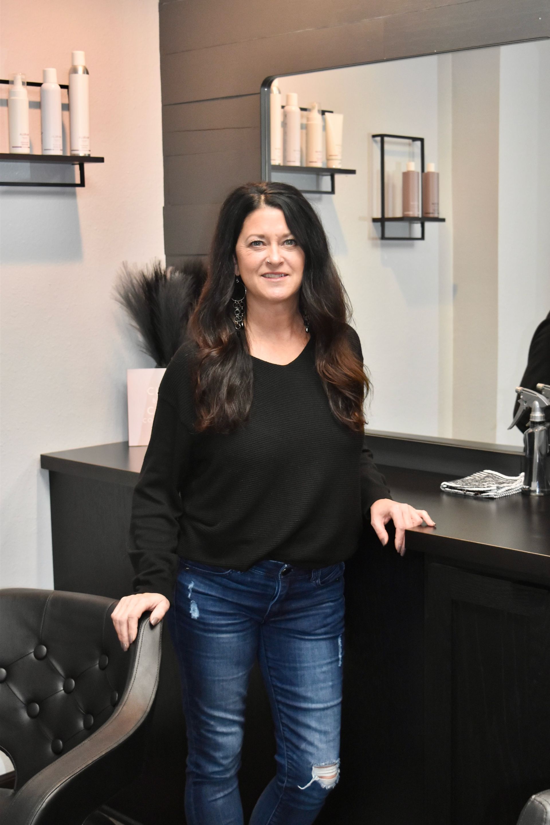 A woman is standing next to a chair in a salon.
