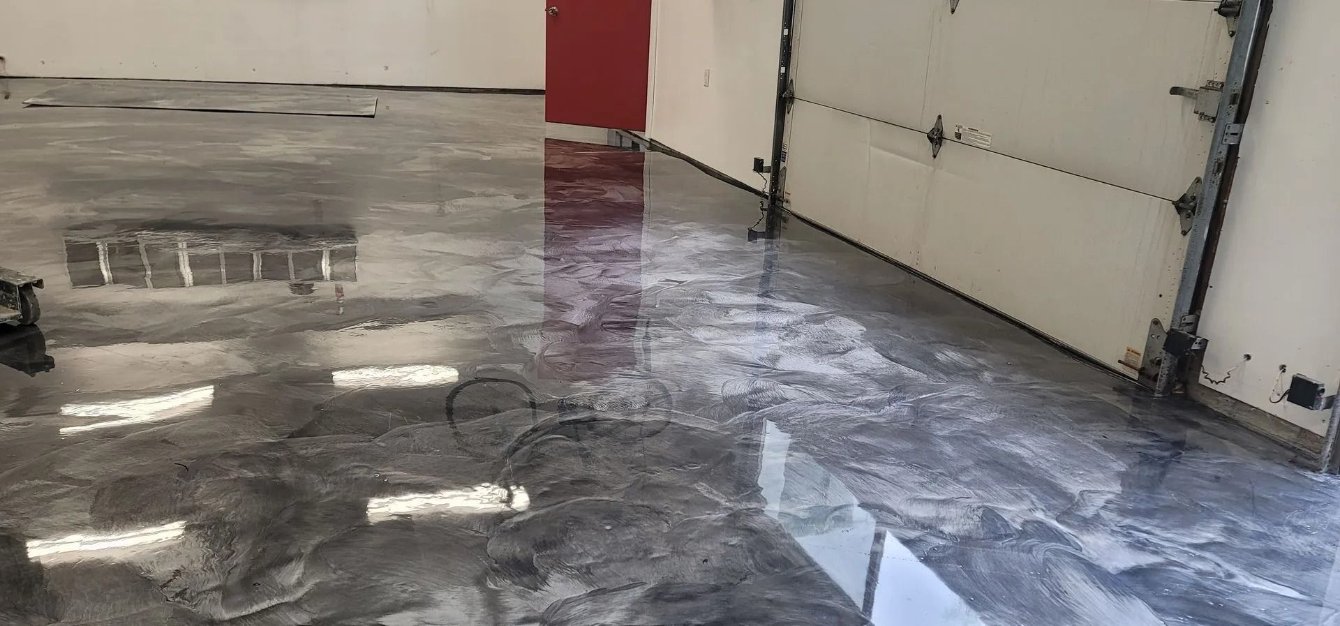 A glossy, grey-and-white marbled epoxy garage floor with reflections of overhead lights.