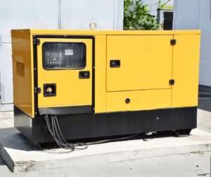 A yellow and black generator is sitting outside of a building.