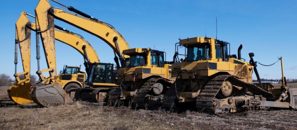 A group of construction vehicles are parked in a field.