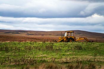A yellow tractor is sitting in the middle of a grassy field.