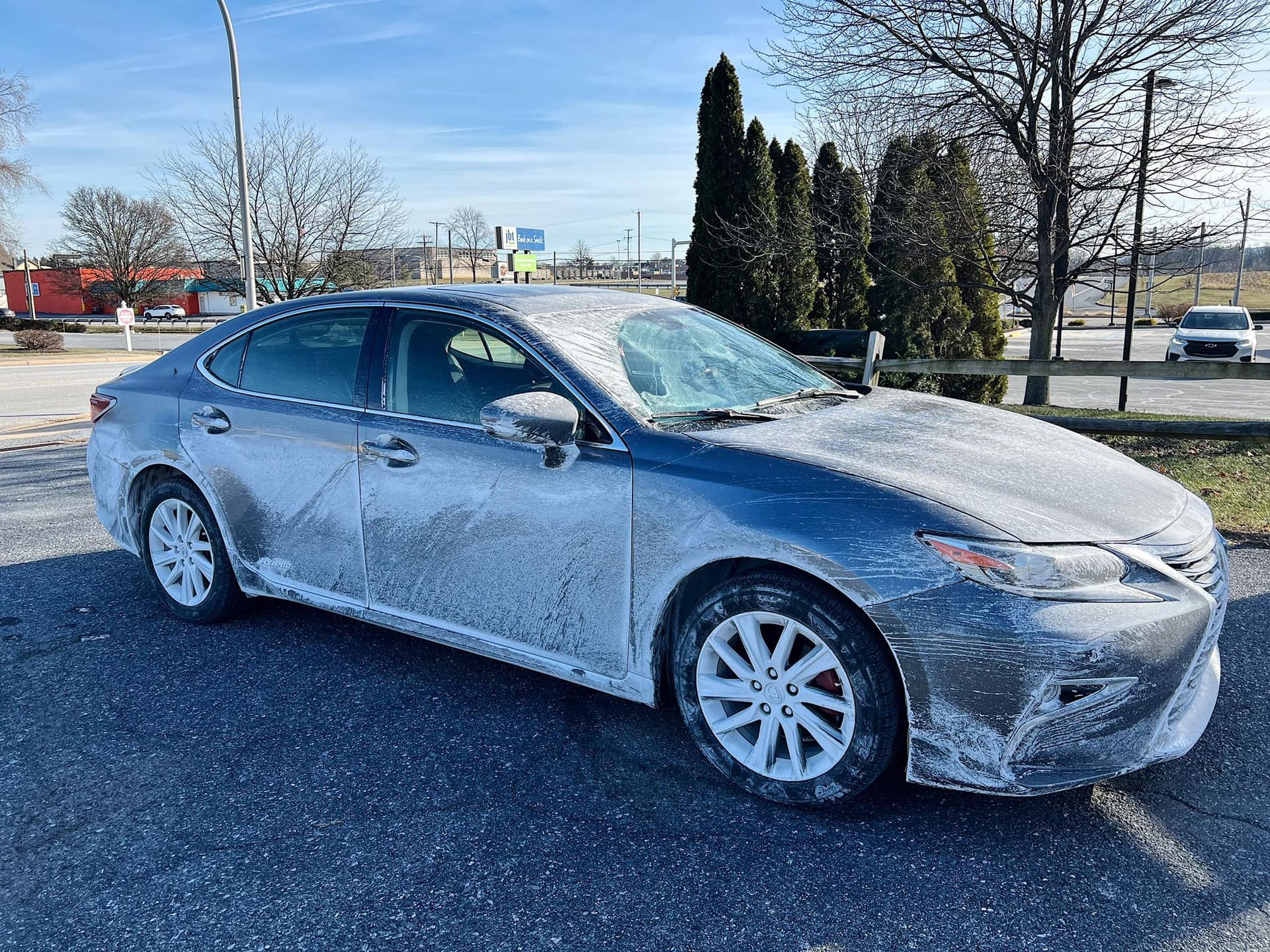Gray sedan covered in frost parked outdoors on a sunny day