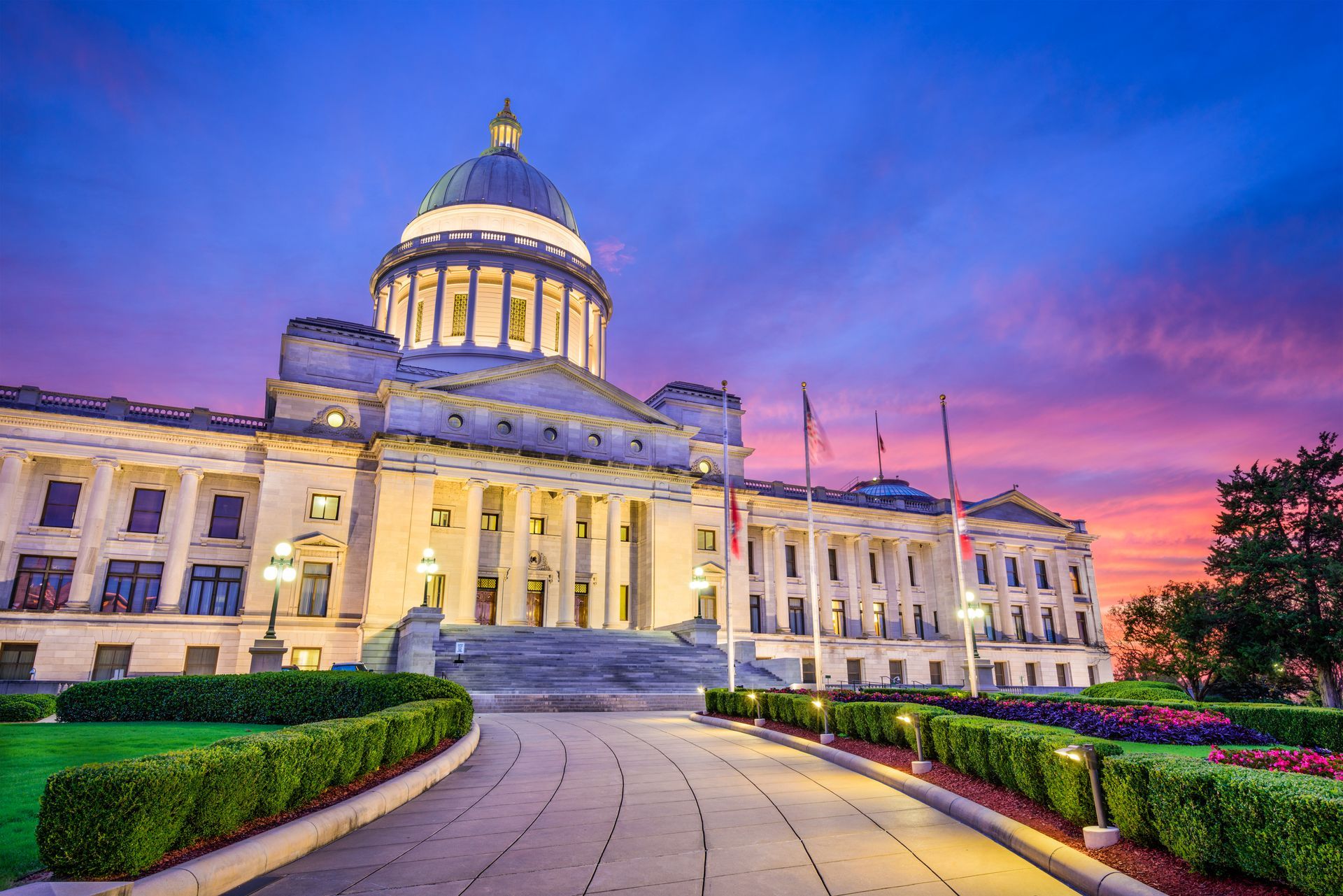A large building with a dome on top of it is lit up at night.