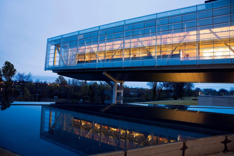 A building with a lot of windows is reflected in the water