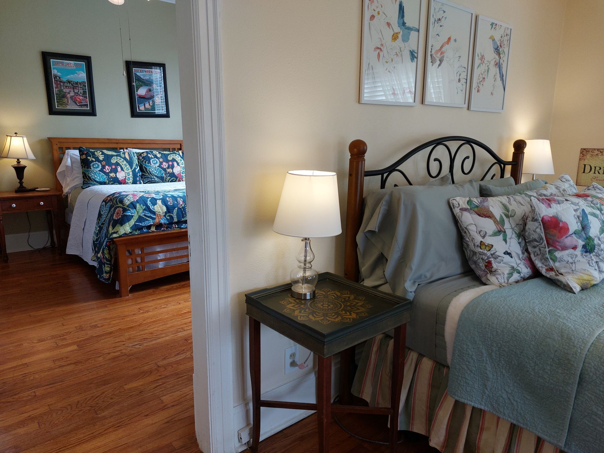 A bedroom with a bed , nightstand , lamps and pictures on the wall.
