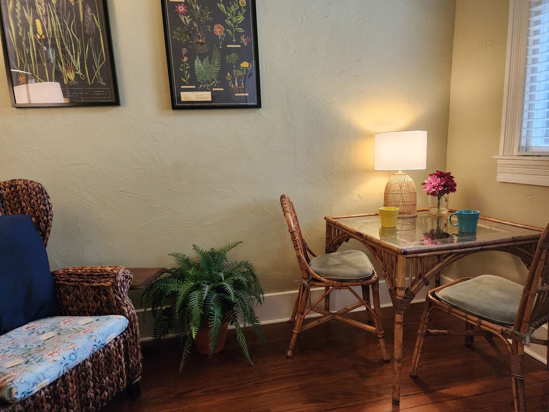 A room with a table , chairs , a lamp and a plant.