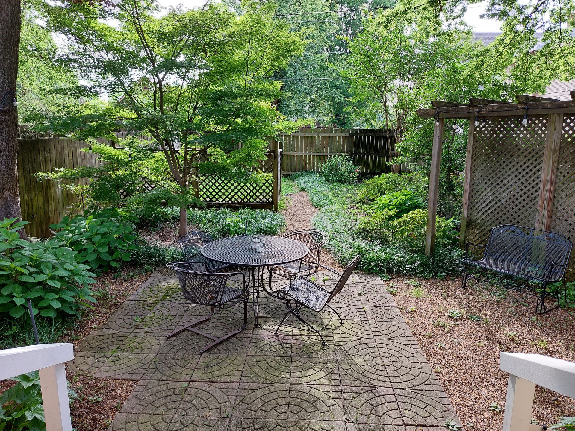A patio with a table and chairs in a garden.
