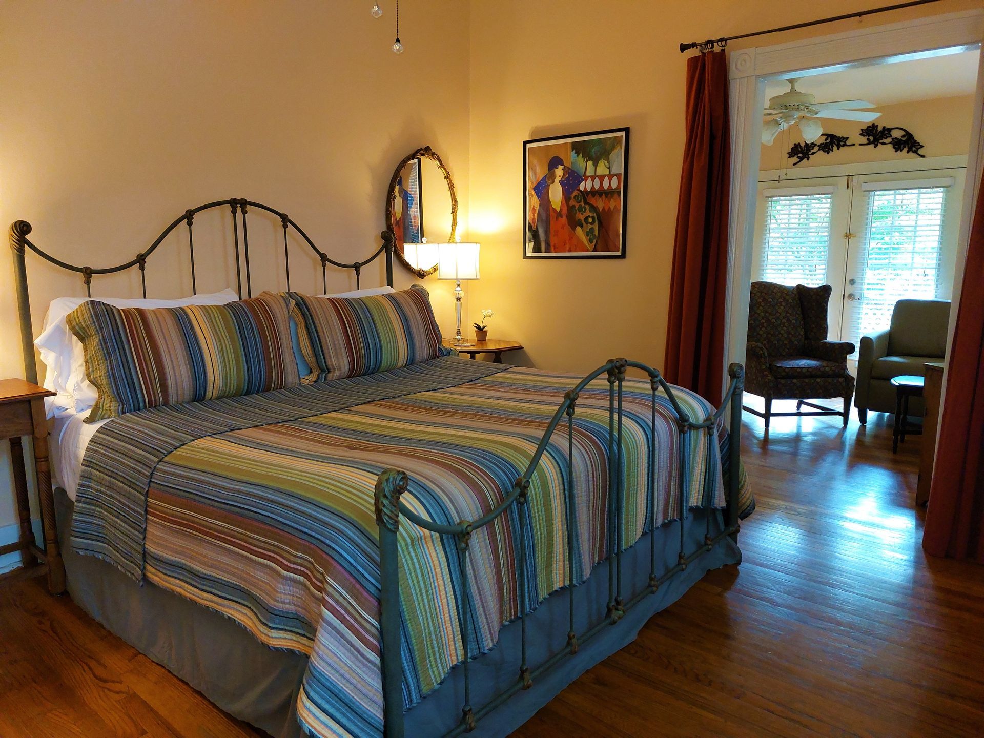 A bedroom with a large bed and a painting on the wall