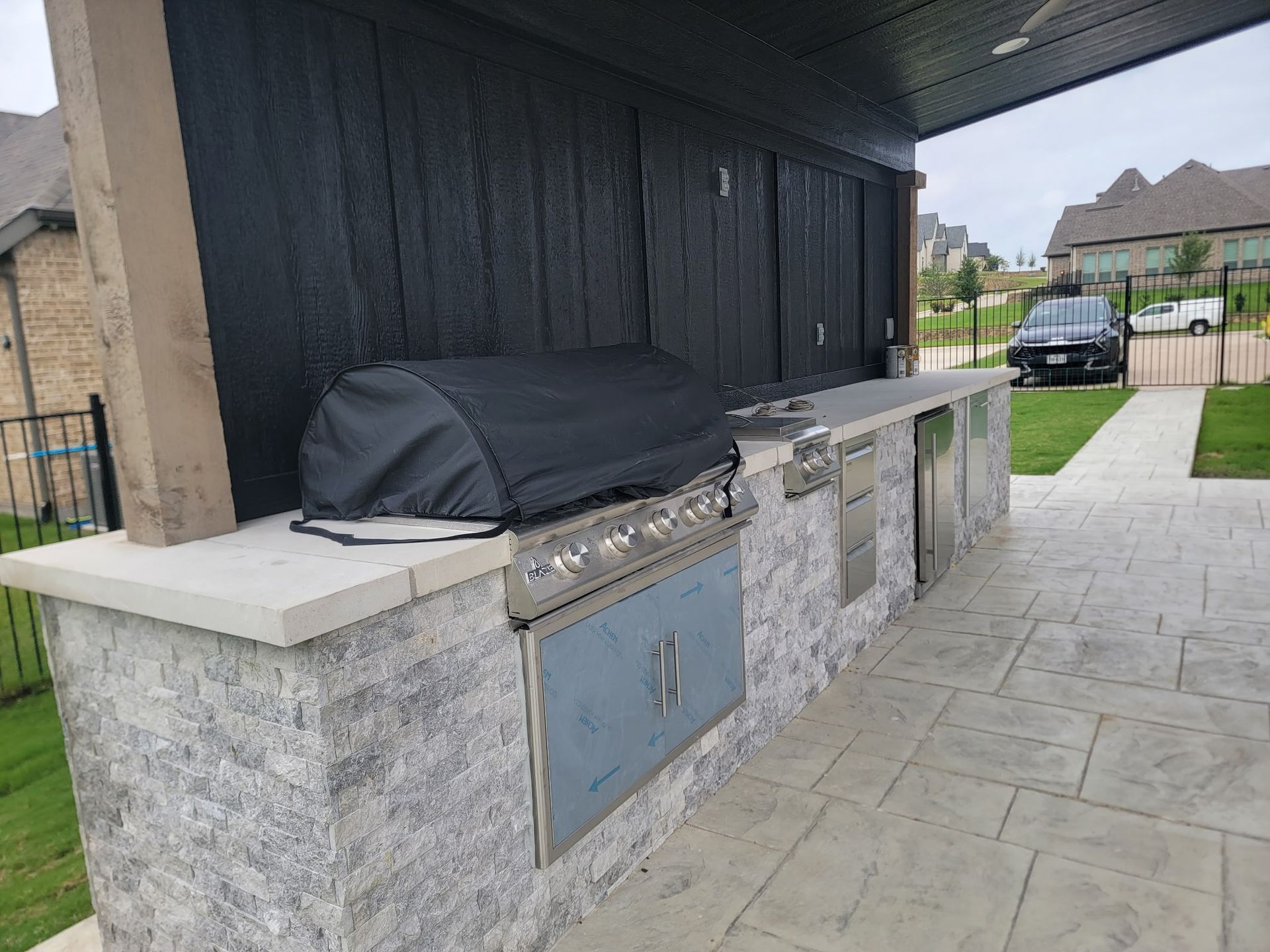 Outdoor patio with built-in grill and stone counters beside a house
