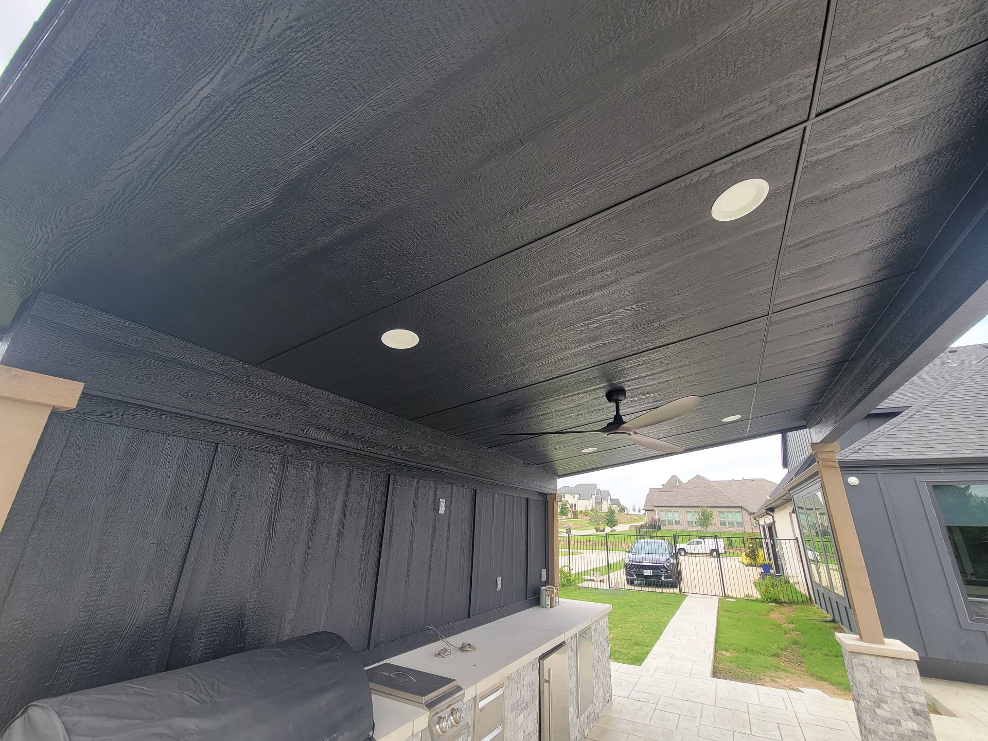 Covered porch with black ceiling, recessed lights, and a driveway view beside a house