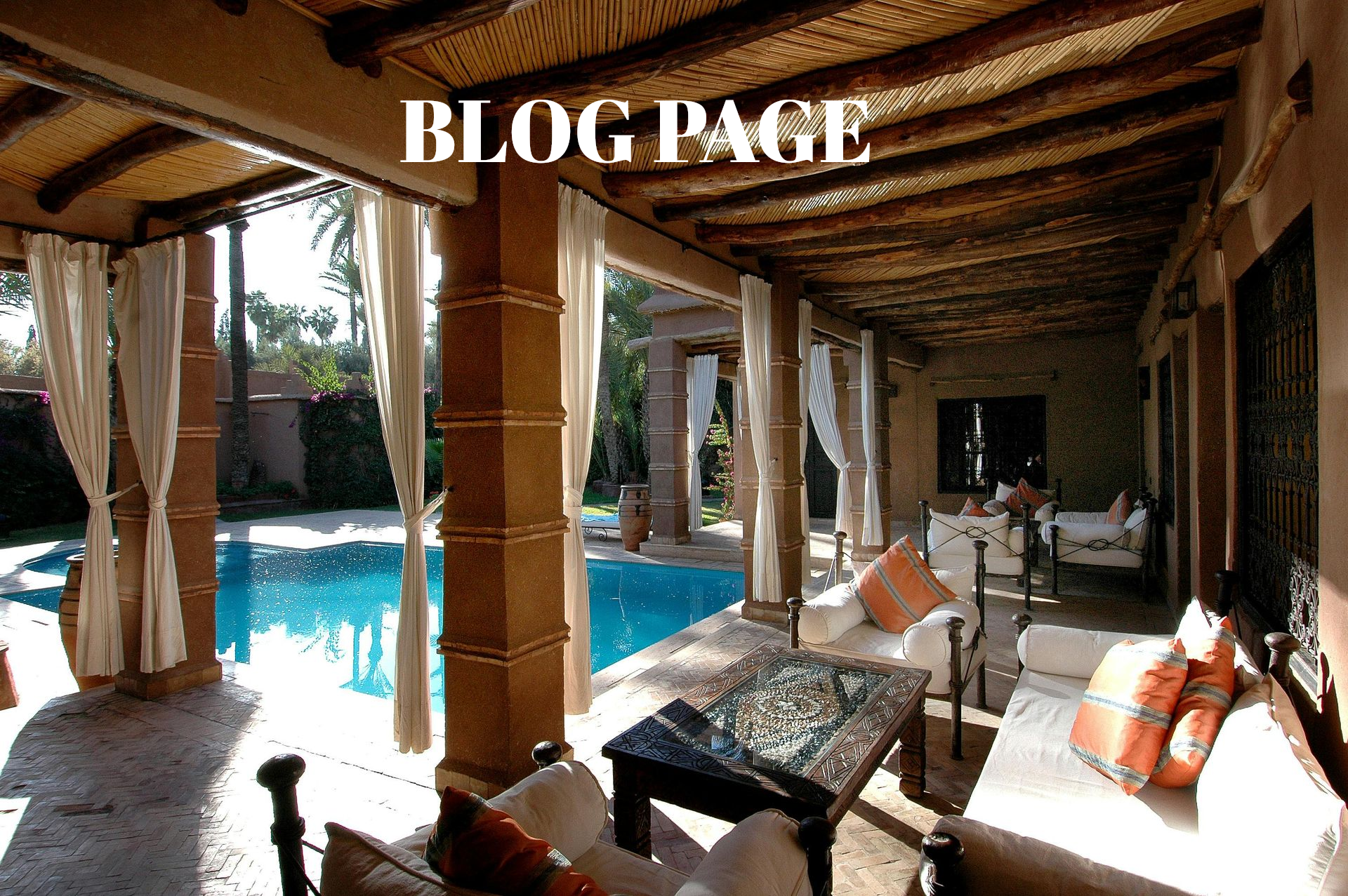 Open-air lounge beside a turquoise pool with rustic wood beams and white curtains