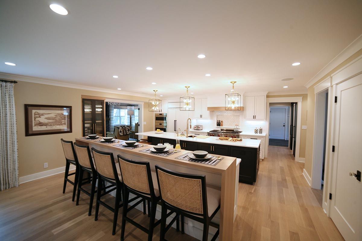 Bright modern kitchen and dining area with a long island, barstools, pendant lights, and wood floors