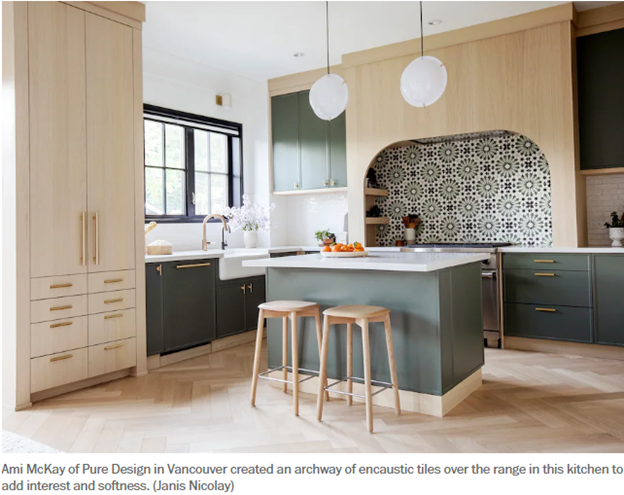 Modern kitchen with light wood cabinetry, dark island, patterned arch backsplash, and two stools