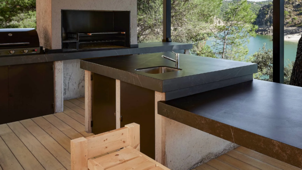 Modern kitchen with large island, dark countertops, wood floor, and a view of water through glass doors