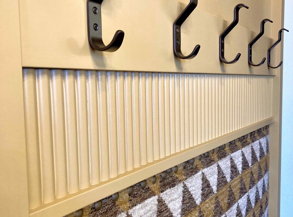 Wall-mounted coat hooks above a cream beadboard and patterned tile backsplash.