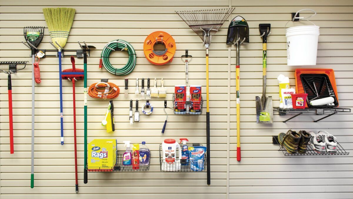 Garden tools and supplies displayed on a slatwall, including rakes, hoses, trimmers, and buckets