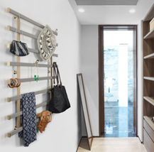 Modern entryway with wall-mounted racks, hanging bags and scarves, and a glass door at the end.