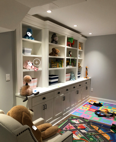 Built-in toy storage and shelves in a playroom with stuffed animals, a chair, and a colorful play mat